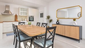 Una cocina moderna con armarios blancos, una mesa de comedor de madera y sillas negras.