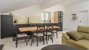 Una cocina moderna con comedor, un sofá y una puerta con un bolso colgado.