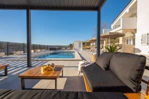 Un espace piscine aménagé sur le toit, avec un canapé, une table et des chaises longues.