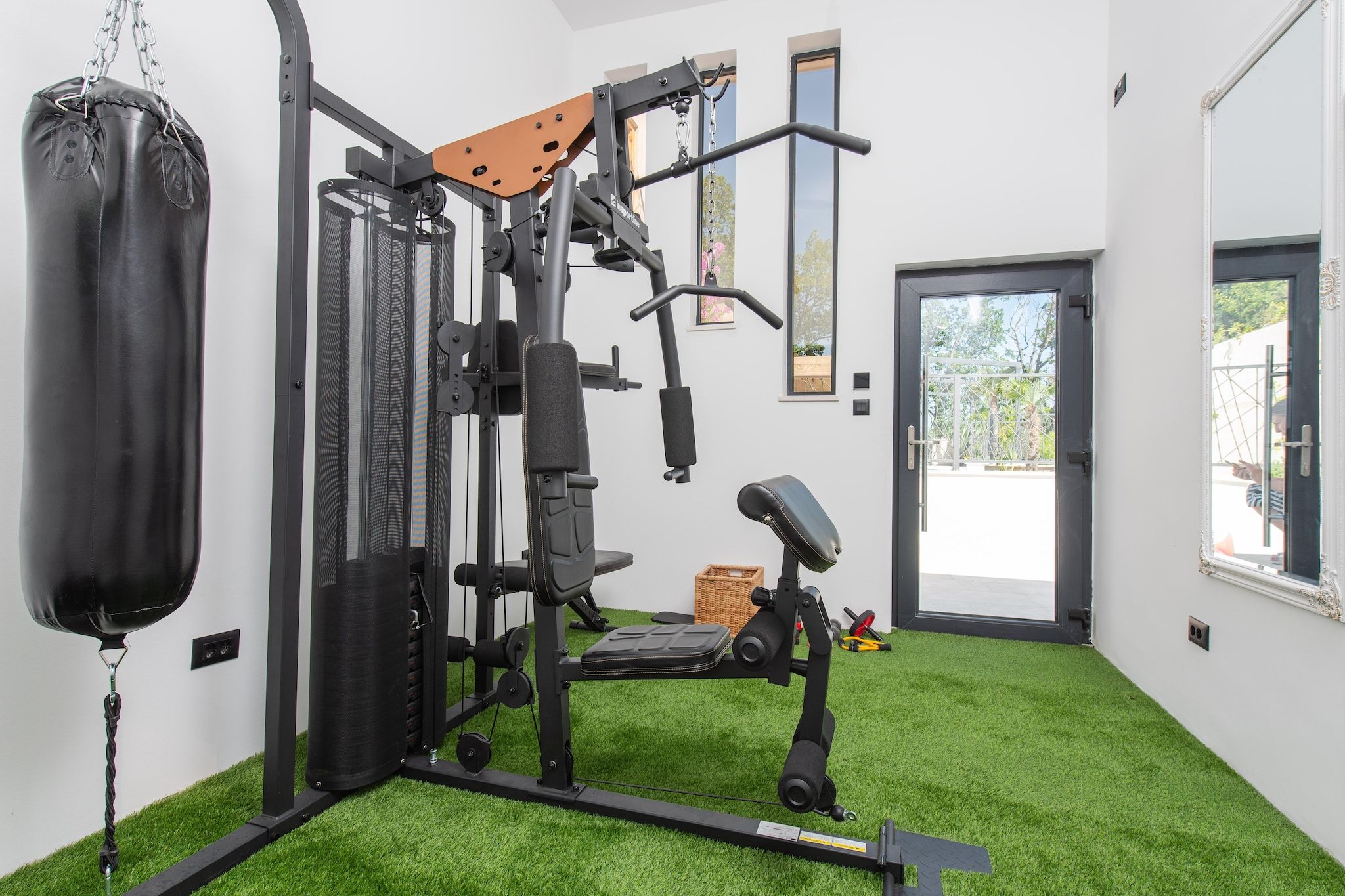 A home gym with a punching bag, weight bench, and various exercise equipment.