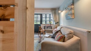 Een gezellige woonkamer met een bank, een houten stoel en een tafel met een bloevas.