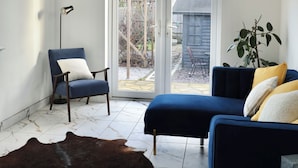 Una sala moderna con un sofá azul, un tapete de cuero y una silla.