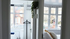 Un pasillo estrecho con piso de madera que conduce a un dormitorio con cama y ventana.