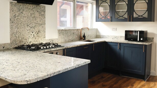 Una cocina moderna con armarios oscuros, encimera de granito y cocina integrada.