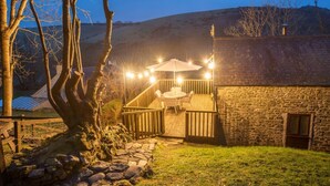 A stone building with a wooden deck and outdoor seating area. - 2 Bed in Llwyndafydd (oc-c31062) (Llandysiliogogo)