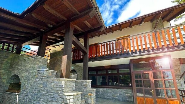 A two-story building with stone walls and a wooden balcony. - HOTEL DU SOLEIL (Mongnod)