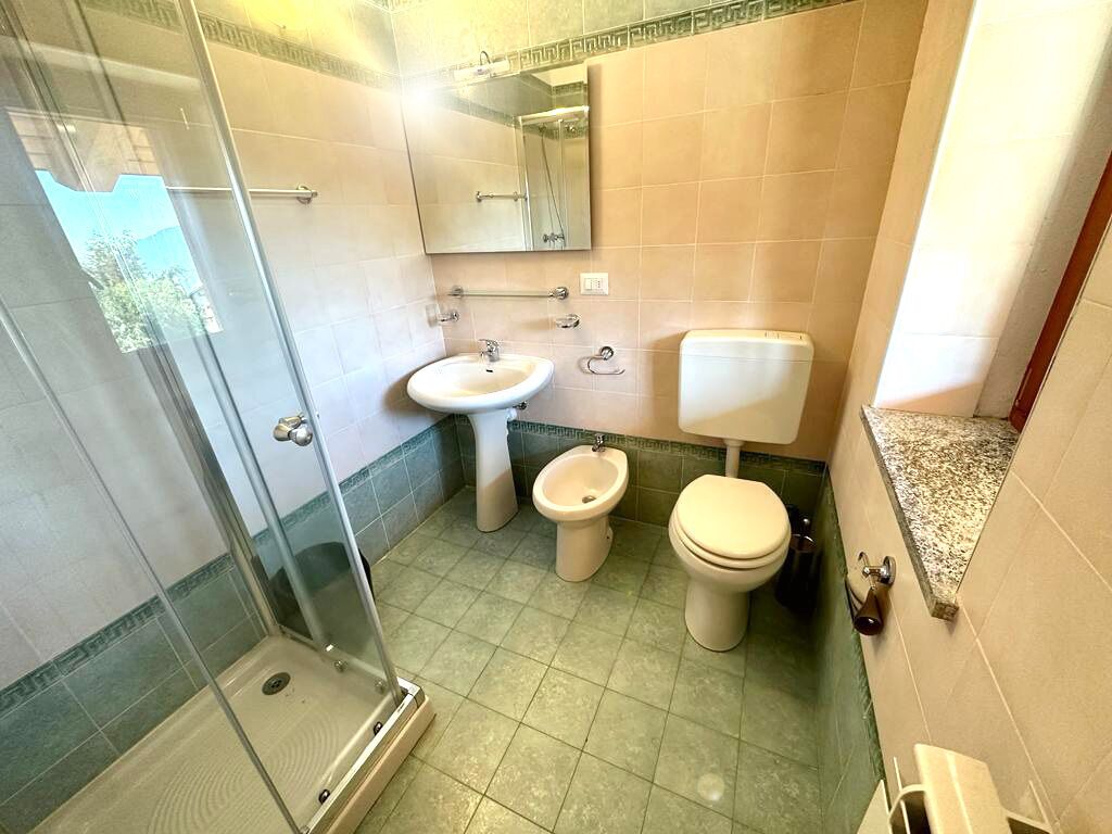 Un baño con ducha envuelta en vidrio, lavamanos, bidé e inodoro.