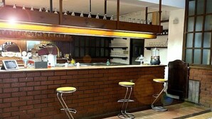 A bar area with a brick counter, stools, and a hanging light fixture. - HOTEL DU SOLEIL (Mongnod)