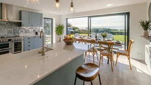 Une cuisine moderne dotée d’un grand îlot central, d’un coin repas offrant une vue agréable et d’une grande fenêtre.