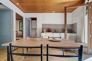 Eine moderne Küche mit Holztisch, Stühlen und Blick in das angrenzende Schlafzimmer.