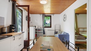 Cozinha compacta com mesa de madeira, uma caixa de lenços de papel e vista para um jardim pela janela.