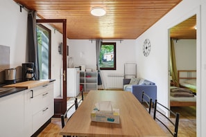 Een compacte keuken met een houten tafel, een zak tissues en uitzicht op een tuin door een raam.