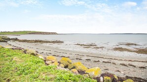 Een kuststrand met een rotsachtige kustlijn en grasvelden.