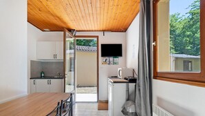 Une cuisine compacte avec un plafond en bois, une table à manger avec des chaises, un lave-linge et un téléviseur fixé au mur.