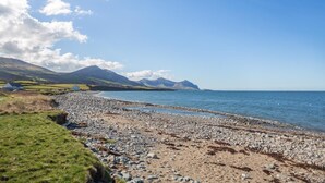 Ein felsiger Strand mit freiem Blick auf das Meer und ferne Berge.