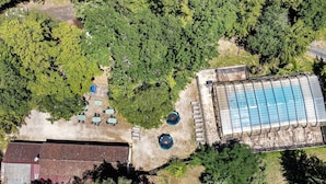 An aerial view of a property with a swimming pool, a covered outdoor seating area, and a building with a sloped roof. - Holiday Home for 7 Guests with Optional Air Conditioning and Shared Pool (Calviac-en-Périgord)