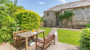 A stone building with a tiled roof, a wooden table with chairs, and a well-maintained lawn. - 2 Bed in Launceston (oc-d31000) (Trevadlock)