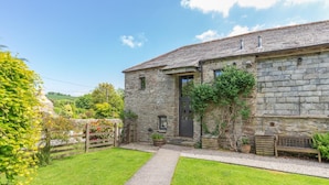 A stone building with a small garden and a pathway leading to the entrance. - 2 Bed in Launceston (oc-d31000) (Trevadlock)