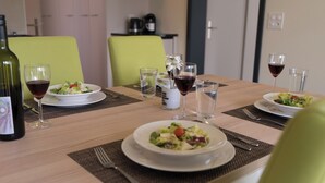 Ein Esstisch, gedeckt mit Salatschüsseln, Weingläsern und einer Weinflasche.