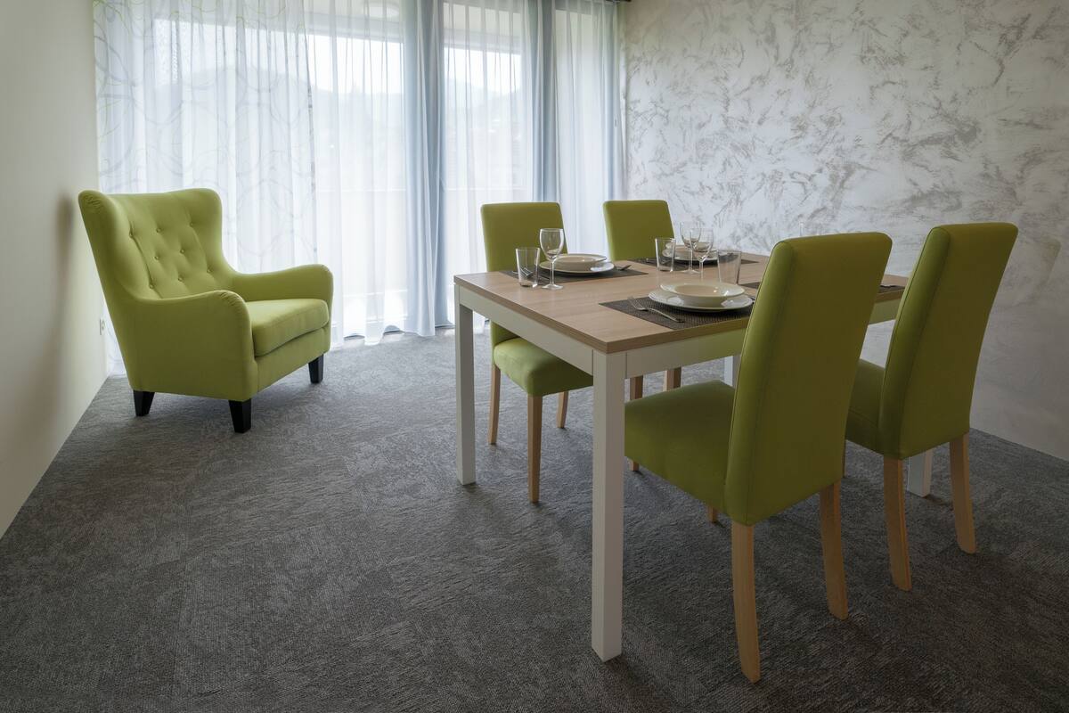 Un coin repas avec une table en bois et quatre chaises vertes.