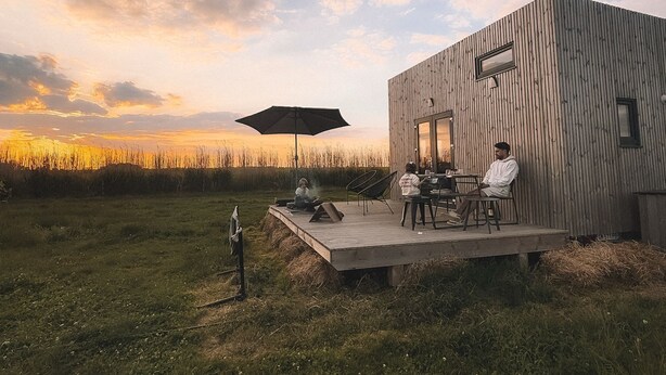 A modern building with a wooden exterior, a deck, and a seating area with chairs and a table. - Tiny house in the heart of the countryside, 1 hour from Paris - calm and a change of scenery guaranteed! (Brégy)