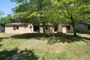 A small building with a tiled roof, a wooden bench, and a tree in front. - Holiday Home “6 People” with Shared Pool (Calviac-en-Périgord)