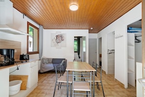A modern kitchen with a wooden ceiling, a dining table with chairs, a sofa, and a painting on the wall. - Holiday Home “6 People” with Shared Pool (Calviac-en-Périgord)