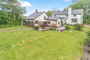 A two-story house with a stone facade and a well-maintained lawn. - 1 Bed in Kilkhampton (oc-j31131) (Pancrasweek)