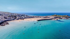 An aerial view of a coastal town with a beach, boats, and buildings. - 3 Bed in St. Ives (oc-sims01) (Carbis Bay)
