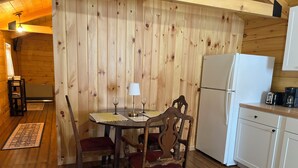 Un interno in legno con un tavolo da pranzo per due persone, un frigorifero e un bancone cucina.