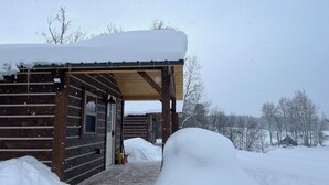 Una baita di legno con un portico coperto e un tetto innevato.