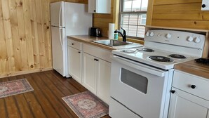 Una cucina con pareti in legno, un frigorifero, un fornello e una finestra.
