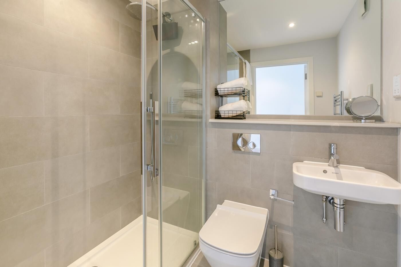 Une salle de bain moderne avec une douche à parois de verre, des toilettes blanches et un lavabo avec un miroir au-dessus.