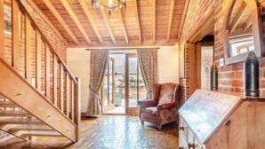 A wooden staircase leading to a room with a brick wall, a patterned armchair, and a wooden cabinet. - 6 Bed in Wangford (oc-e31107) (Wangford)