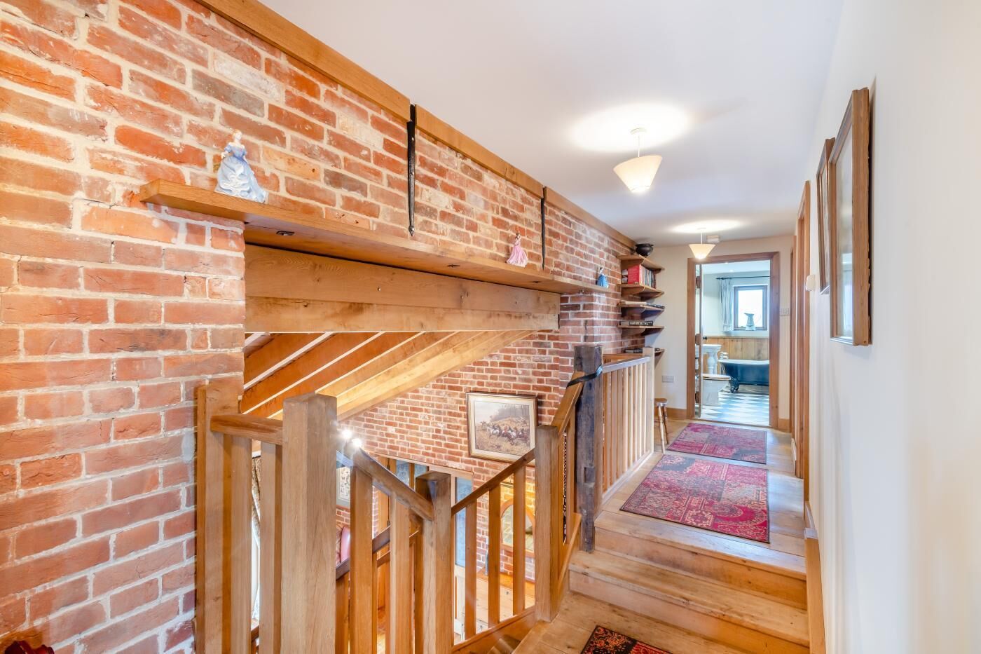 A wooden staircase with a brick wall, a wooden railing, and a red carpet.