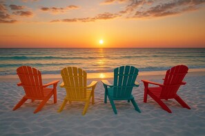 Vier Adirondack-stoelen gericht op de zee tijdens de zonsondergang.