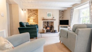 Un salón acogedor con pared de piedra, chimenea y televisor.