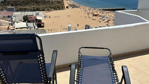 Ein Balkon mit zwei Liegestühlen mit Blick auf einen Strand.