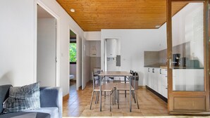 A modern kitchen with a dining area, wooden ceiling, and a sofa with a patterned cushion. - Holiday Home "Maison 4 Personnes" Air Conditioning Available, Shared Pool (Calviac-en-Périgord)