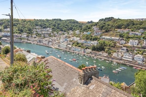 Une ville côtière dotée d’un port de plaisance rempli de bateaux, entourée de bâtiments résidentiels et de verdure.