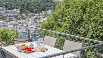 A balcony with a table set for two, overlooking a cityscape and a river.