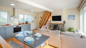 Eine moderne Küche mit Essbereich, einer Treppe und einem Wohnzimmer mit Sofa und Fernseher.