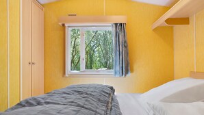 Une chambre avec un lit, une fenêtre avec des rideaux et une armoire.