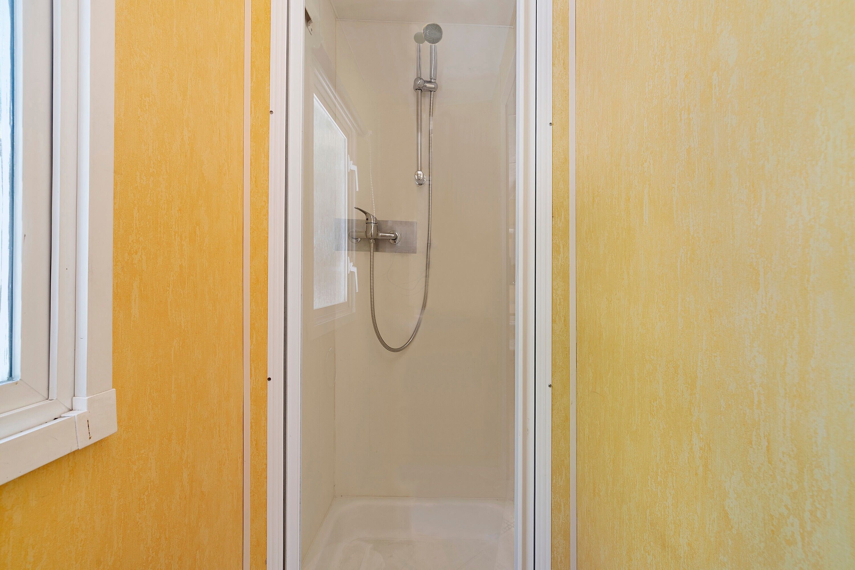 A shower with a handheld showerhead and a wall-mounted faucet.