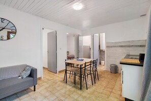 Una cocina compacta con una mesa, sillas, un sofá y un reloj de pared.