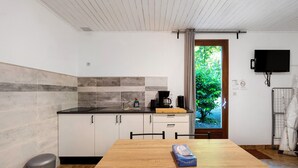 Een moderne keuken met een houten tafel, een prullenbak en een aan de muur bevestigde televisie.