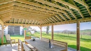 Un pabellón de madera con una mesa y bancos, con vista a un campo cubierto de césped.