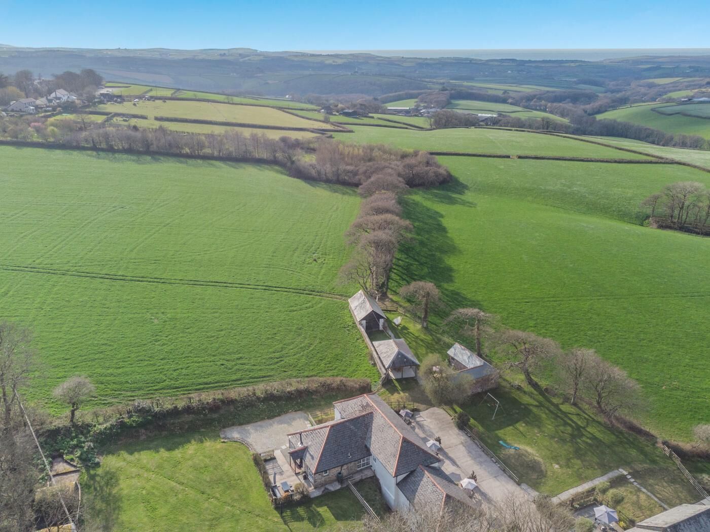 A rural property with a farmhouse, a large green field, and a small pond.
