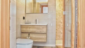 Ein modernes Badezimmer mit einem Holzausziehtisch, einer Toilette und einem großen Spiegel.