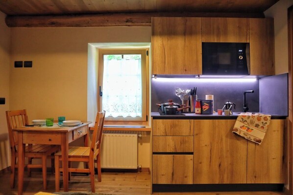 A compact kitchen with wooden cabinets, a built-in microwave, and a small countertop. - Ciesa Le Crepedele Miniappartamento Mirandola (Sottoguda-Palue)